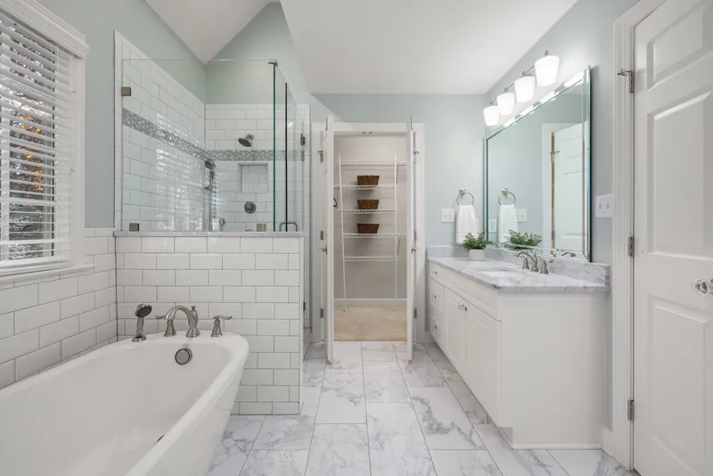 Bright bathroom with a white vanity, marble-look counter and glass shower