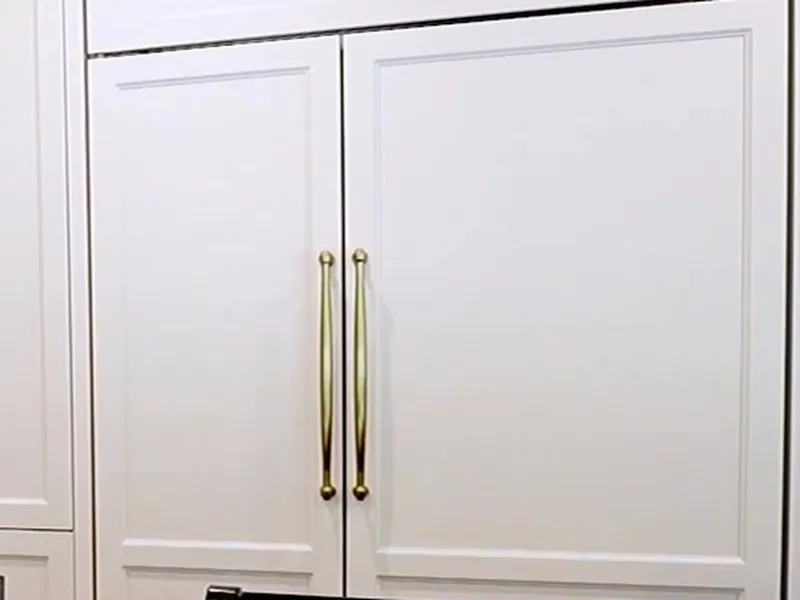 Close-up of gold pulls on finished white cabinet doors